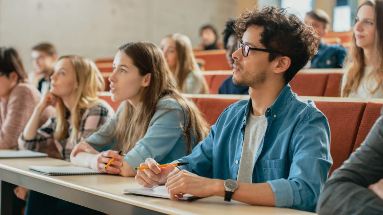 Studenten im Vorlesungssaal hören zu und schreiben mit