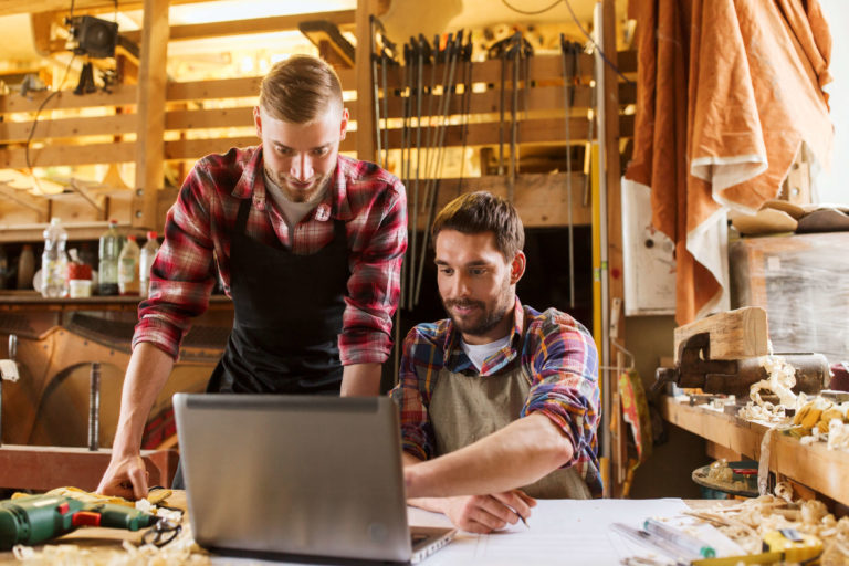 Handwerker zeigt anderem Handwerker blauarbeit.de auf einem Laptop