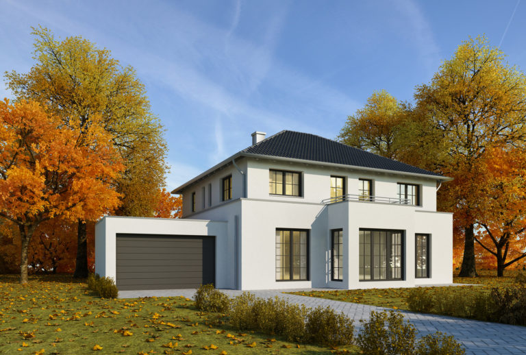 Walmdach auf einem modernen Haus, umringt von herbstlichen Bäumen