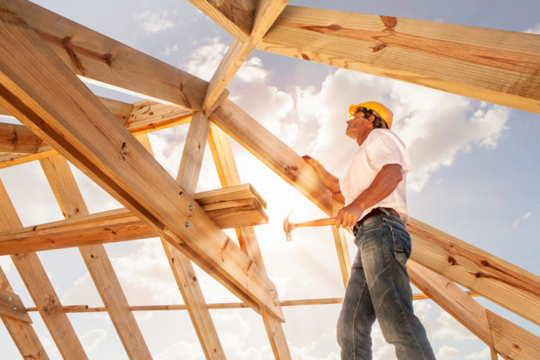 Handwerker im Dachstuhl arbeitet in der Sonne