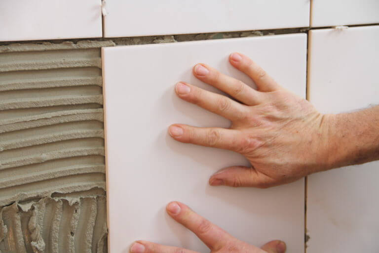 Handwerker beim Wandfliesen verlegen