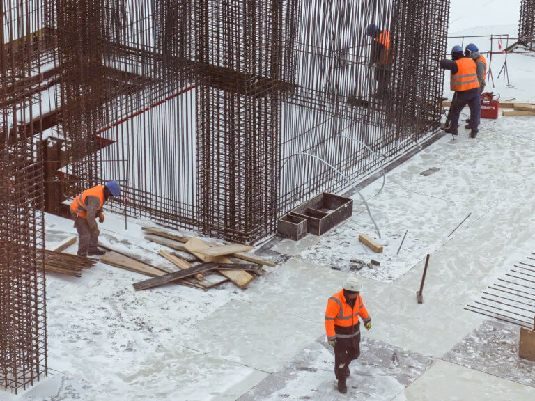 Bauarbeiter mit Warn- und Schutzkleidung arbeiten im Winter auf einer Baustelle