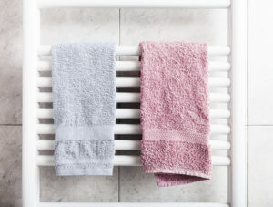 Zwei Handtücher hängen über einem Röhrenheizkörper im Bad