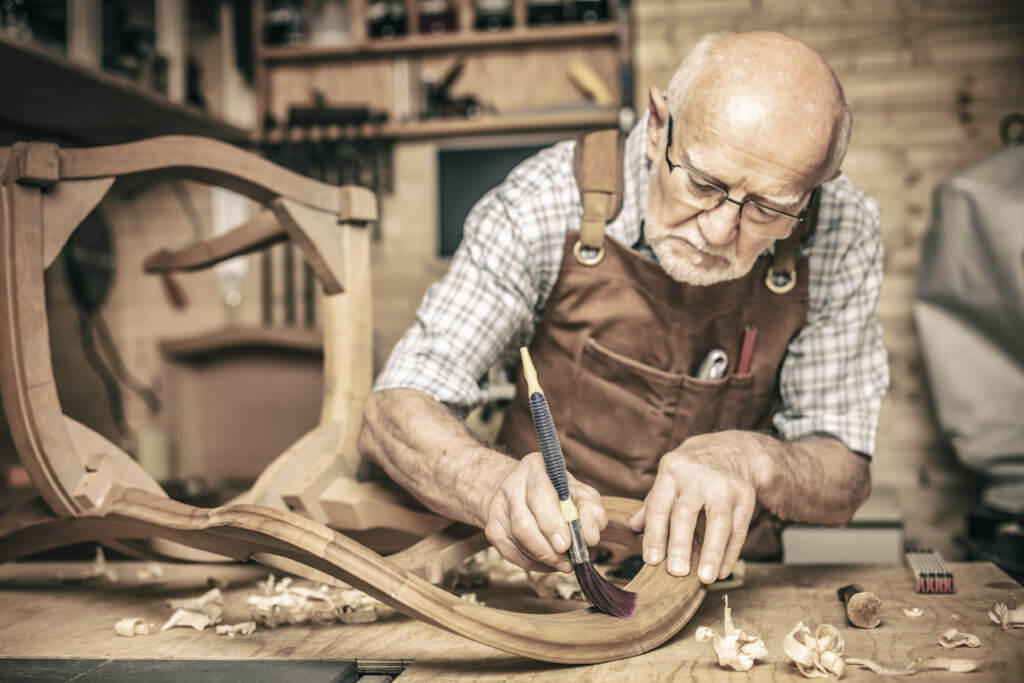Ein alter Tischlermeister fertigt einen Stuhl an