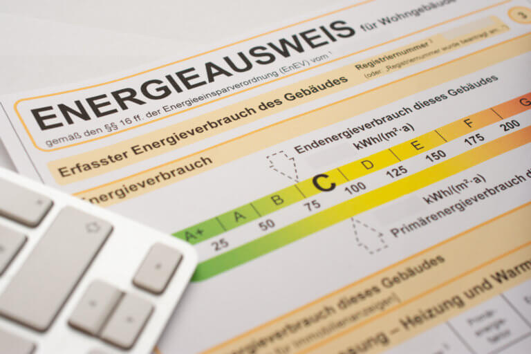 Ein Energieausweis und ein Laptop liegen auf einem Tisch