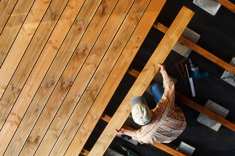 Terrassenbauer während er eine Holzterrasse baut.