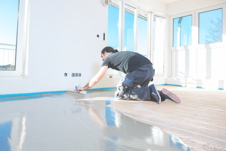 Estrichleger verlegt flüssigen Zementestrich in einem Neubau