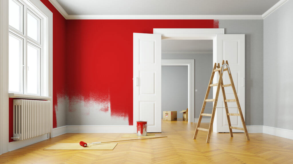 Beim Streichen der Wohnung wird eine Wand mit roter Farbe gestrichen