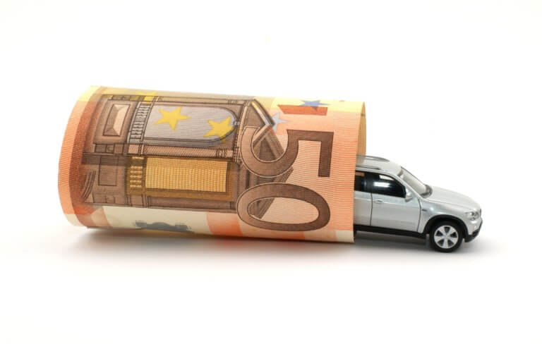 Symboldbild für Fahrtkosten: Ein Spielzeugauto, um das ein 50-Euro-Schein gewickelt wurde