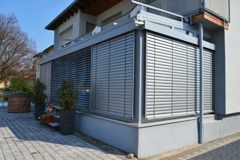 Verglaster Wintergarten mit elektrischen Rollläden als Beschattung an einem Wohnhaus