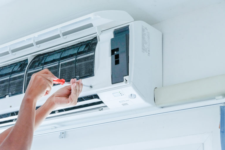 Handwerker schraubt an einer Klimaanlage