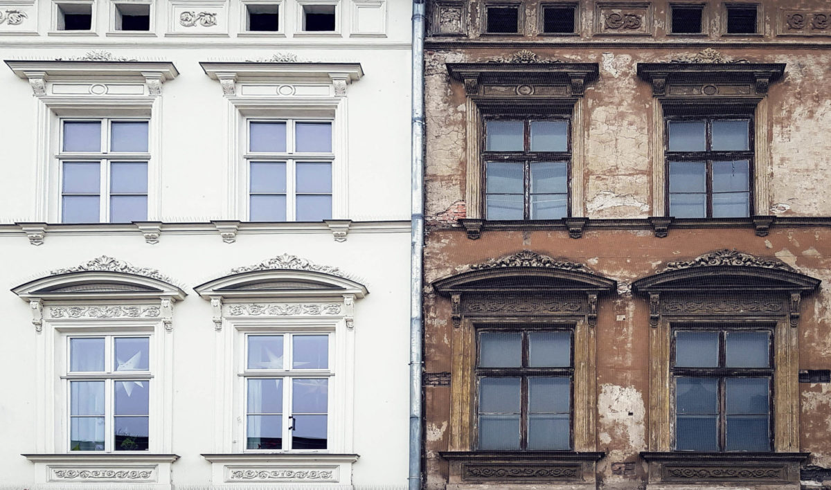 Fassadensanierung eines Altbaus - rechts mit brauner, bröckelnder Fassade und links die neue Fassade mit weißem Anstrich