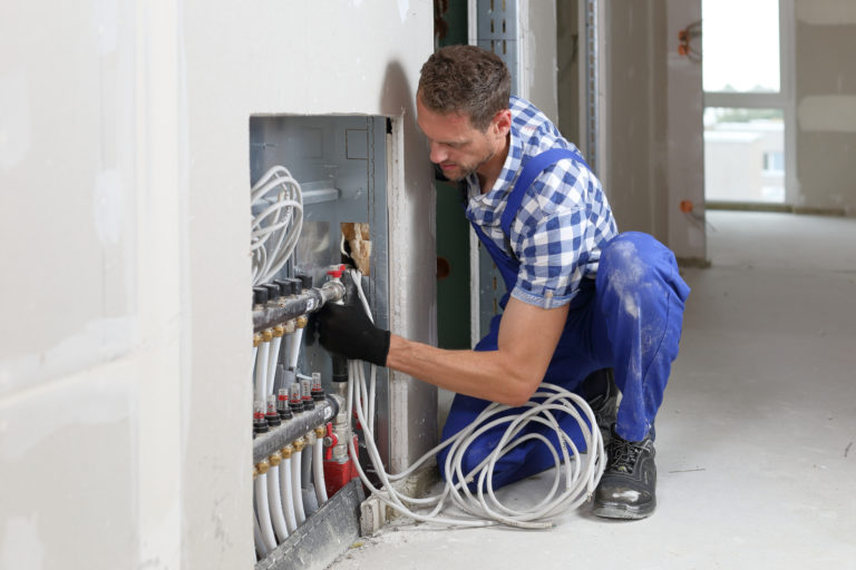 Heizungsbauer bei der Installation einer Fußbodenheizung