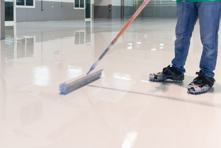 Handwerker gießt einen weißen Epoxidharzboden