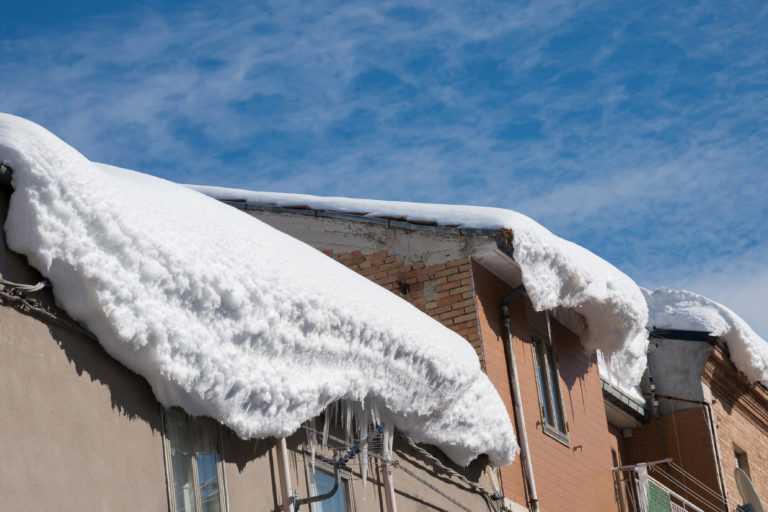 Schneemassen als Dachlawine am Rand eines Daches