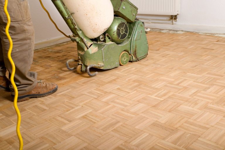 Handwerker schleift einen Parkettboden ab