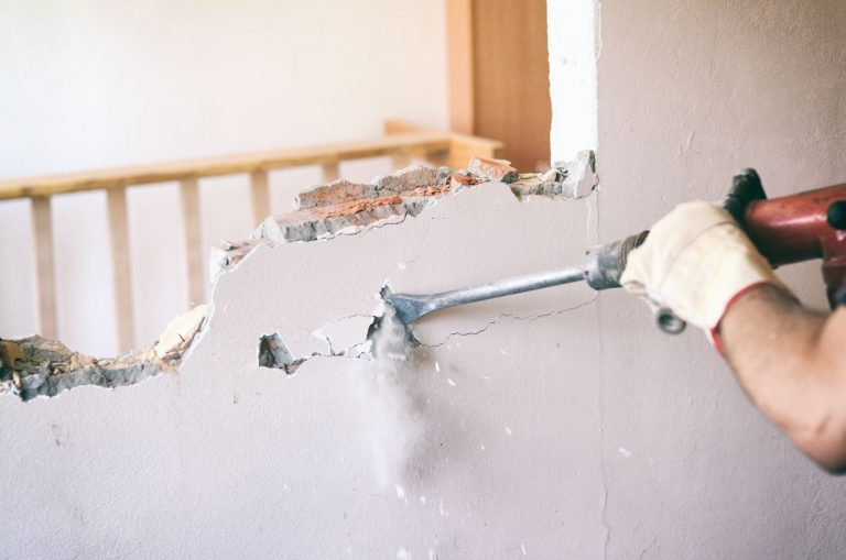 Handwerker erstellt einen Wanddurchbruch in einer Mauer