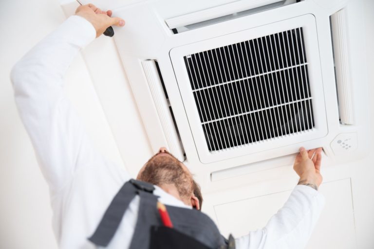 Klimatechniker beim Einbau einer Klimaanlage in der Zimmerdecke