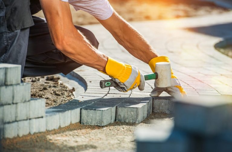 Pflasterer nutzt einen Hammer zum Anlegen eines Gartenwegs