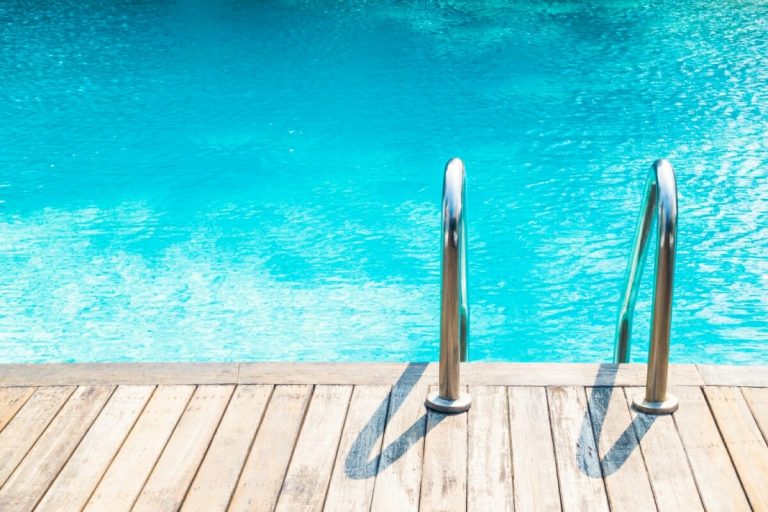 Leiter an einem Pool mit Holzumrandung/Holzterrasse