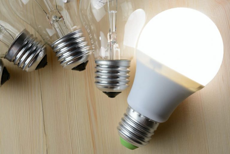 Drei Glühbirnen liegen neben einer hellen LED-Lampe