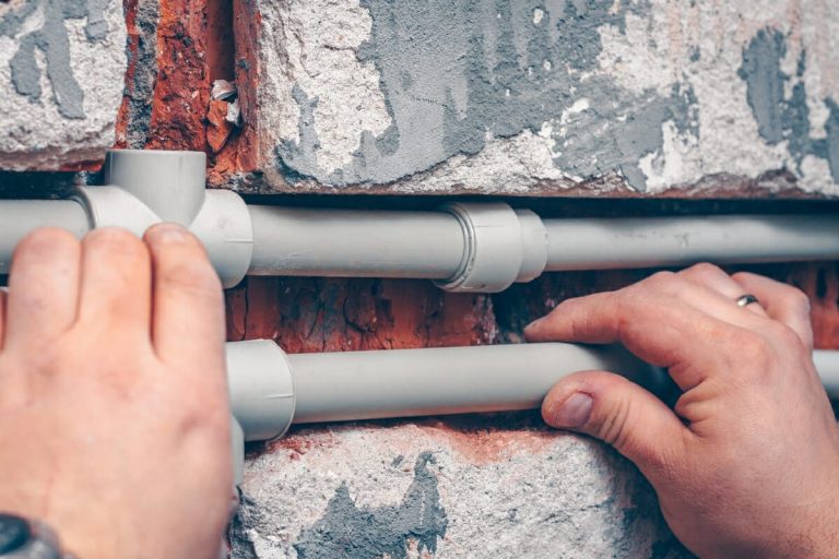 Sanitärinstallateur verlegt Kunststoffrohre in einer Wand