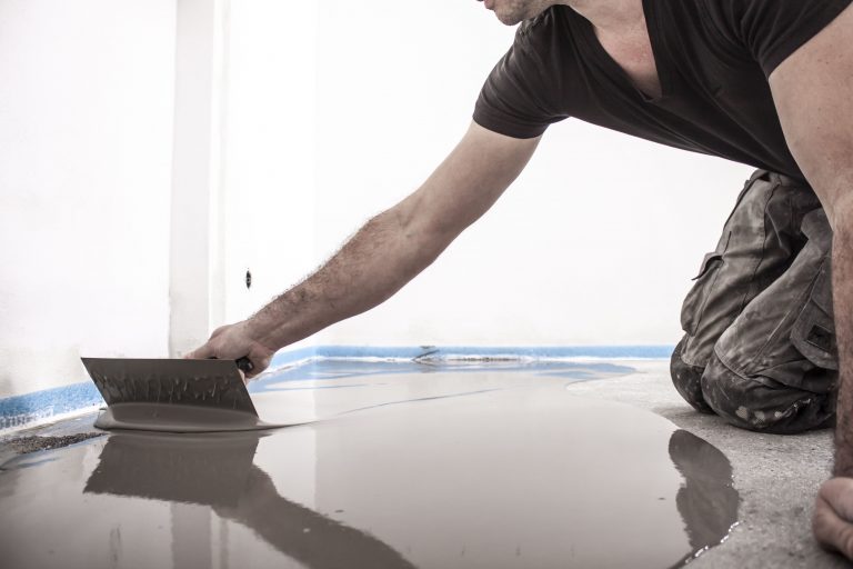 Um einen neuen Boden zu verlegen, muss ein Handwerker den Boden ausgleichen.