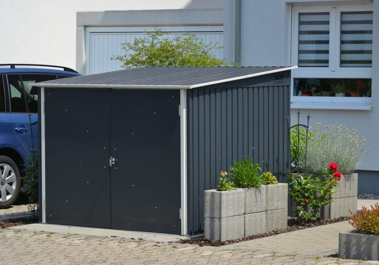Schwarze Fahrradgarage/Fahrradunterstand neben einem parkenden Auto