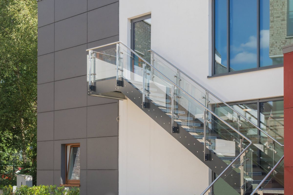 Modere Außentreppe aus Glas und Metall an einer Fassade.