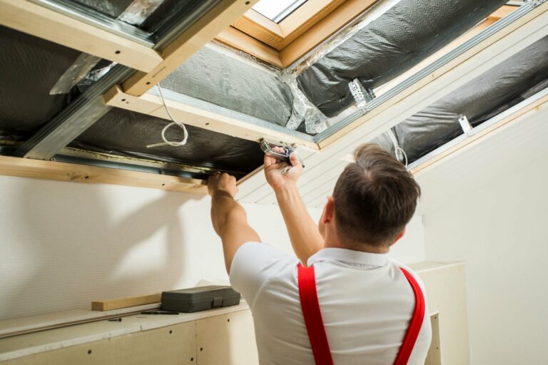 Handwerker beim Anbringen von Deckenpaneelen (Dachbodenausbau)