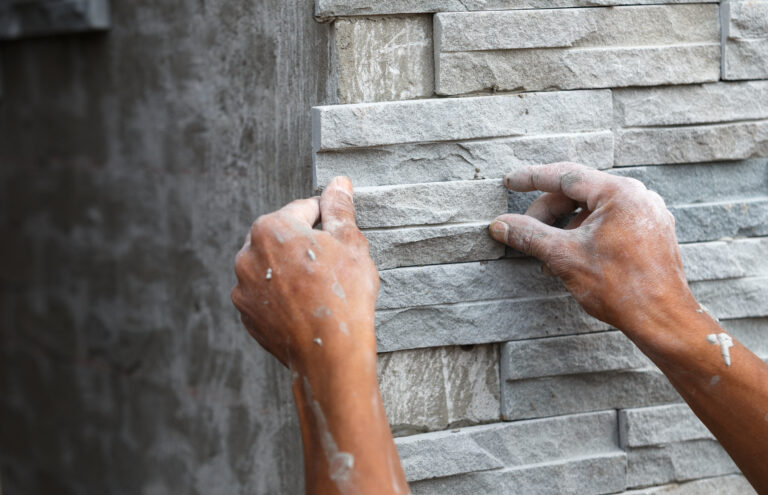 Handwerker bringt Natursteinfassade an.