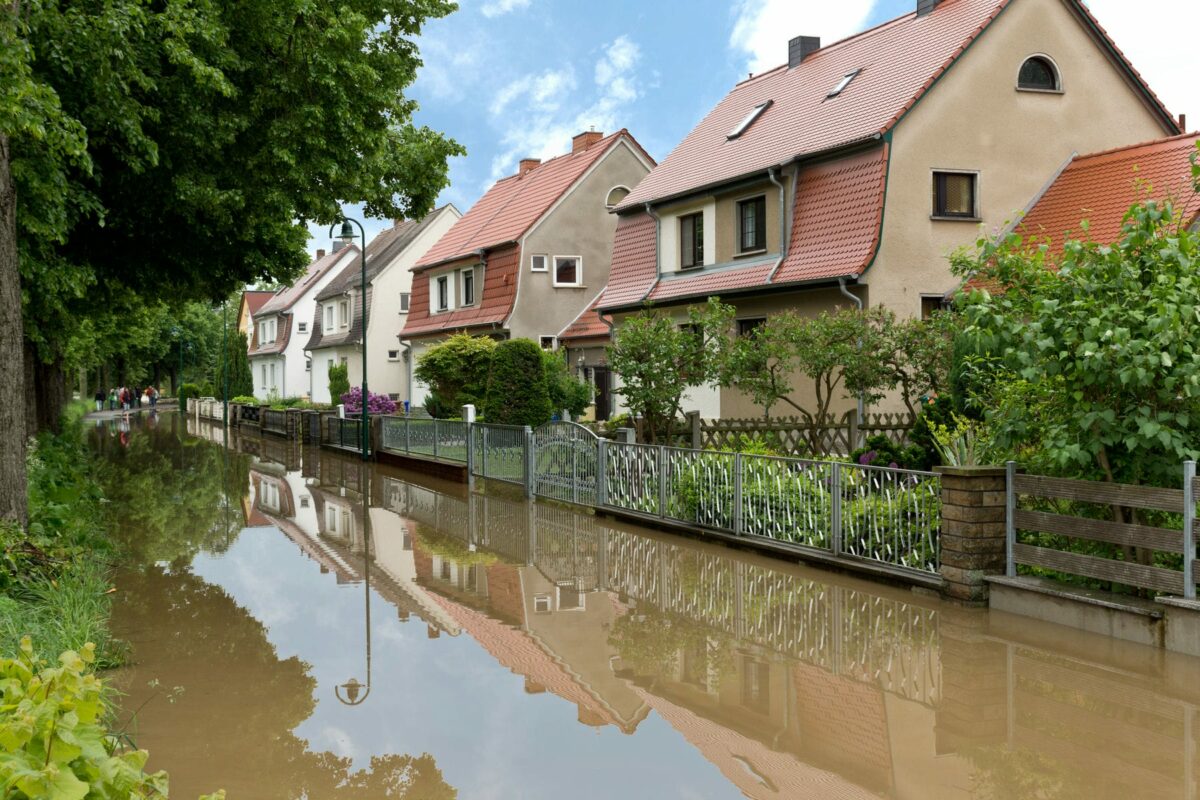 Überflutung einer Straße nach Starkregen, braunes dreckiges Wasser vor einem Haus