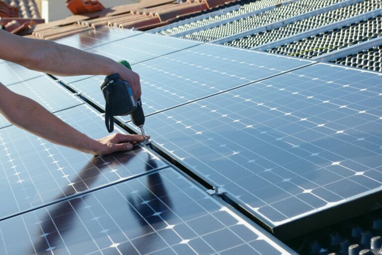 Handwerker schraubt ein Photovoltaikpaneel am Gerüst fest