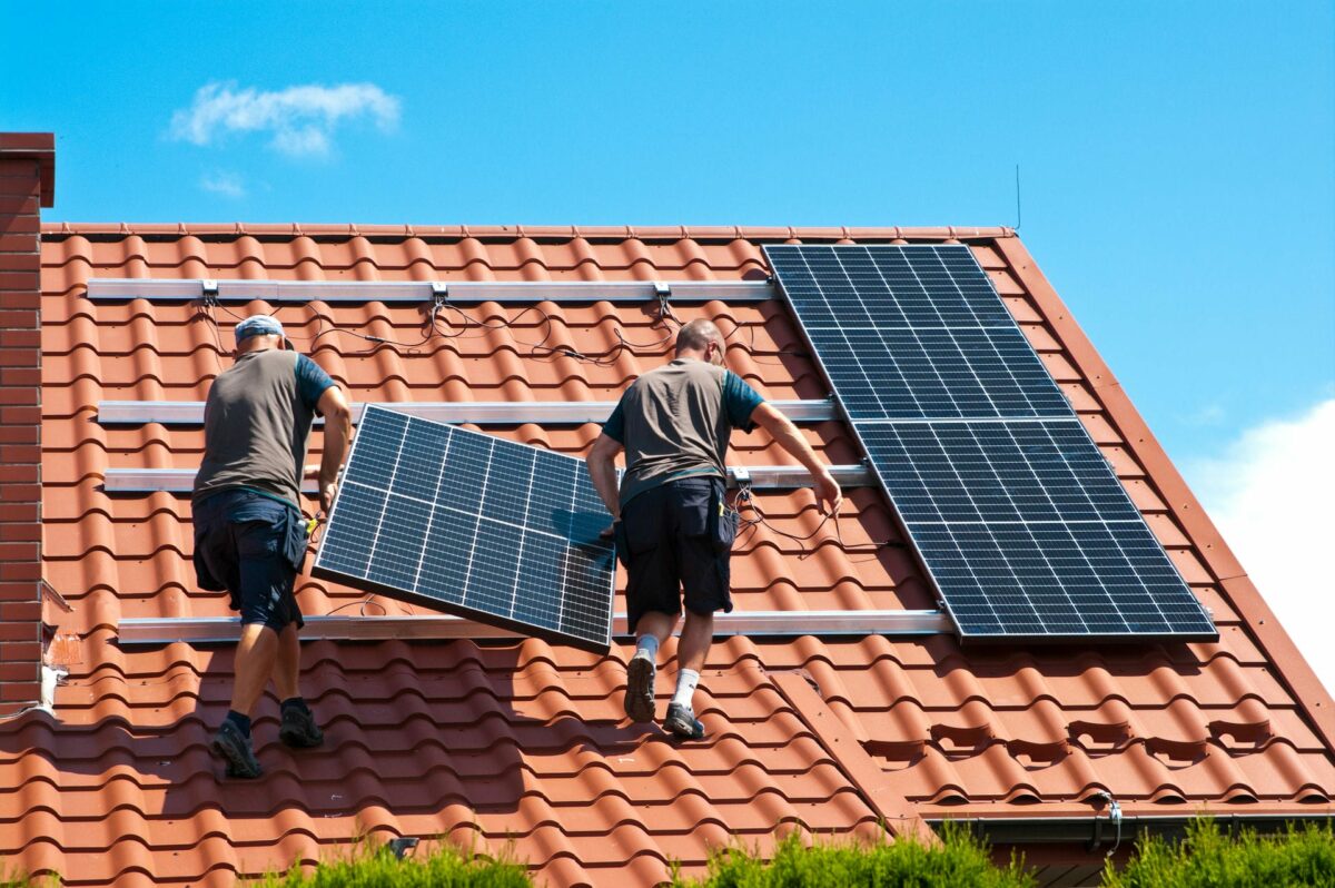 Zwei Handwerker installieren Solarpaneele auf einem Dach