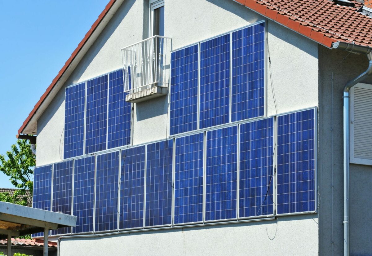 Eine weiße Fassade mit 16 blau schimmernden Solarpaneelen