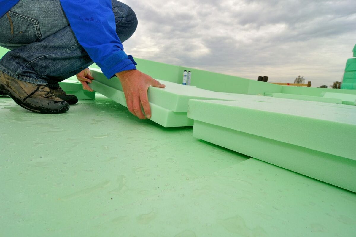 Handwerker bringt hellgrüne Dämmung für eine Thermobodenplatte an