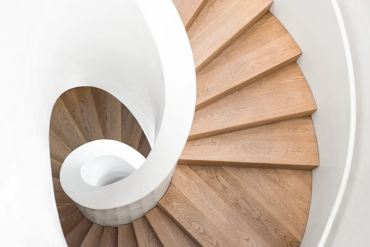 Eine Wendeltreppe mit Stufen aus Holz und weißem Geländer