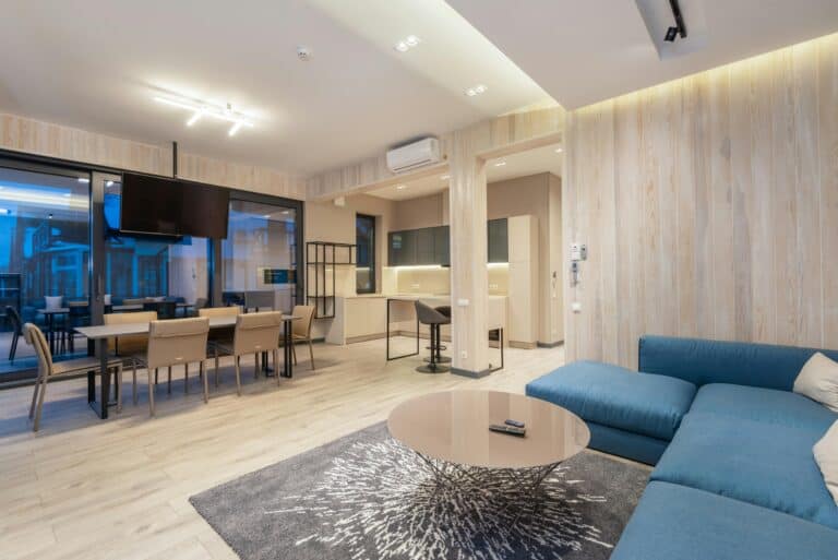 A stylish modern living and dining area with blue sofa and open kitchen. Ideal for urban housing design inspiration.
