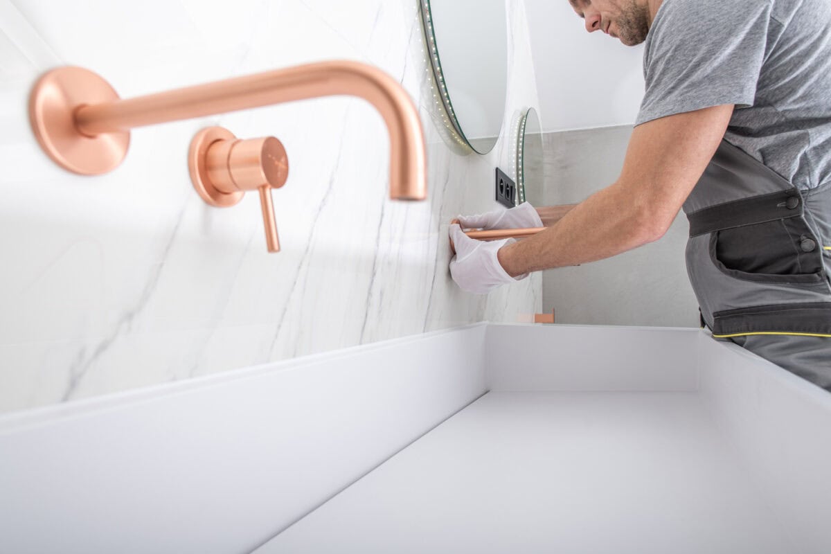 Ein SHK Monteur installiert einen Wasserhahn am Waschbecken.