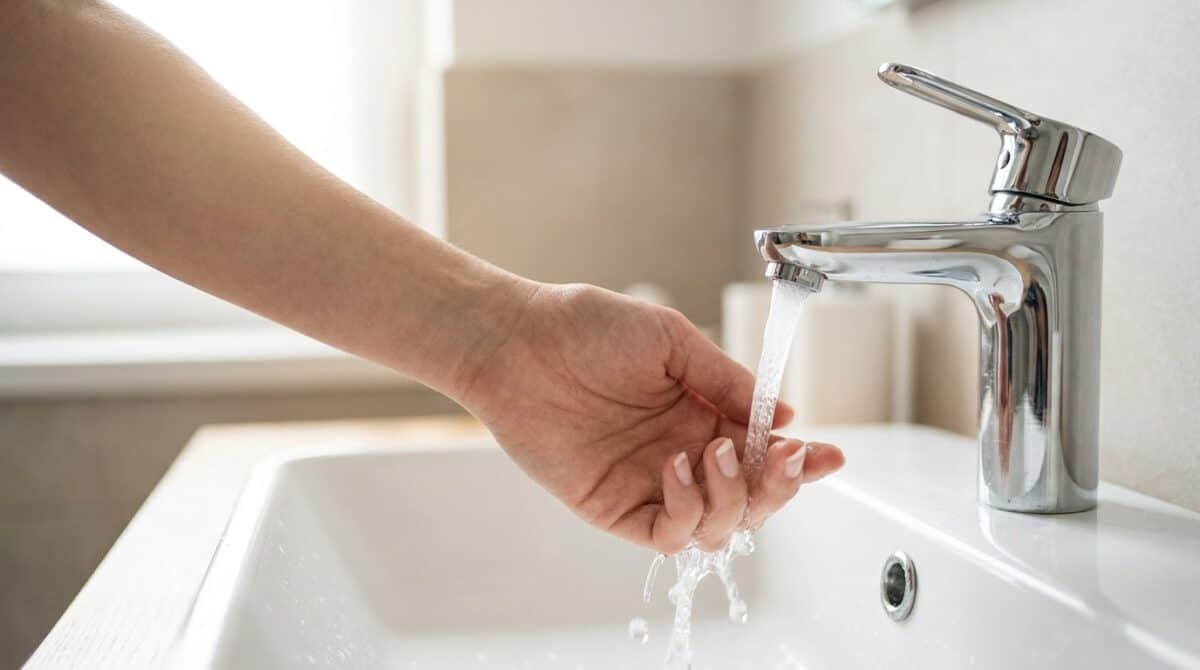 Warmwasser wird nicht warm: Hand prüft die Temperatur unter dem laufenden Wasserstrahl der Armatur