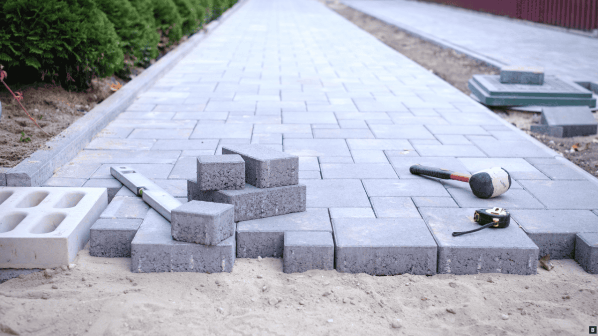 Ein Gehweg wird mit grauen Steinen gepflastert