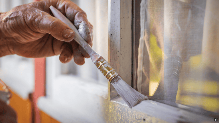 Ein Holzfenster wird weiß gestrichen