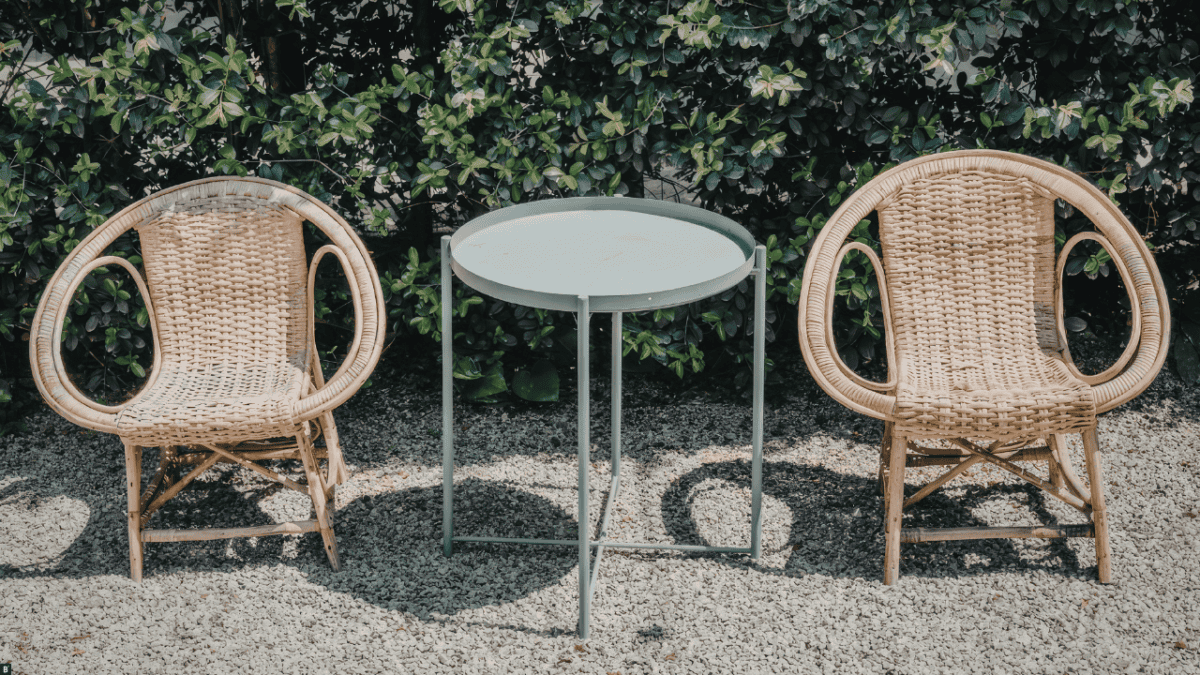 Zwei Rattanstühle und ein Beistelltisch auf Kies