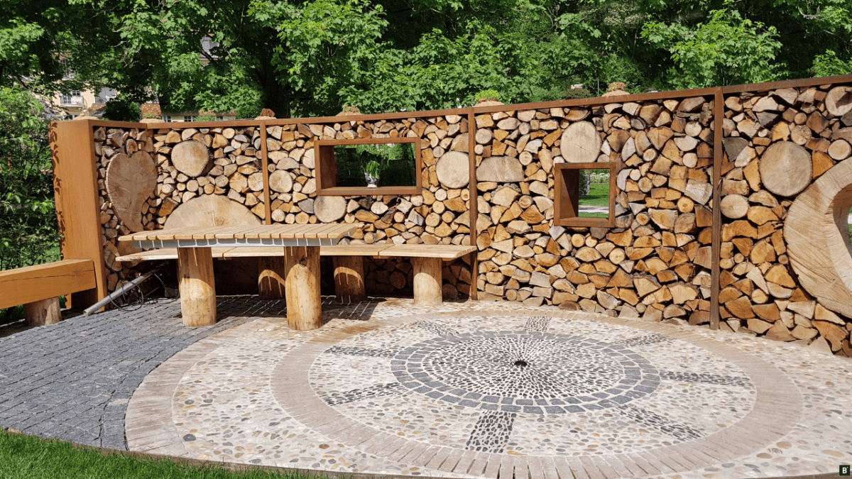 Im offenen Garten dienen mit Holz gefüllte Metallrahmen als Sichtschutz.