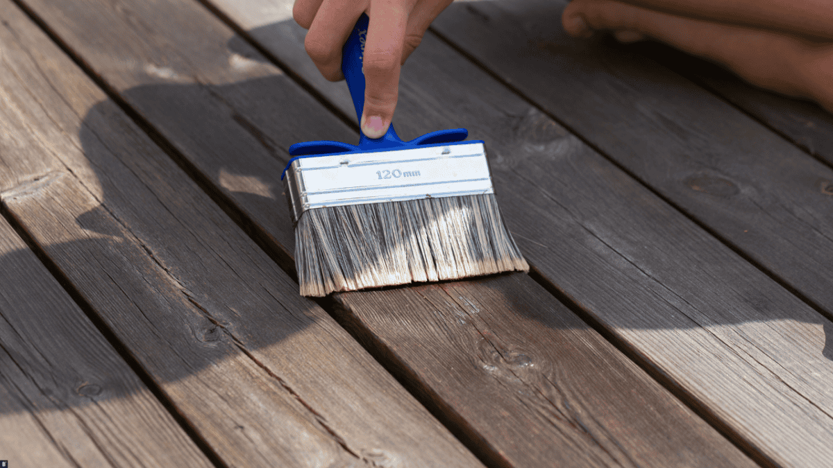 Ein Pinsel wird über ein Holzbrett geführt