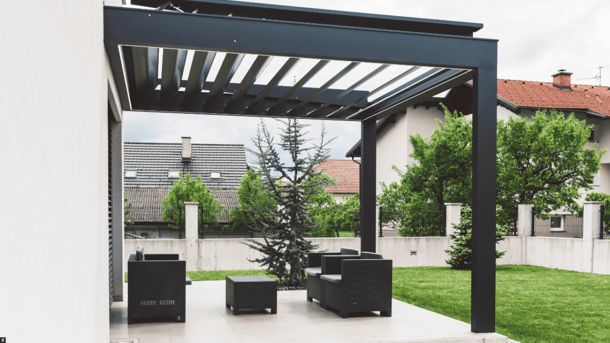 Eine schwarze Terrassenüberdachung aus Aluminium auf einer Terrasse mit schwarzen Möbeln