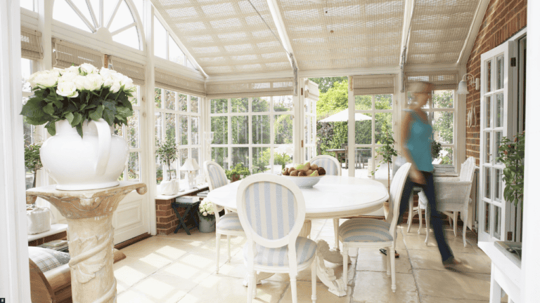 Ein, heller Wintergarten mit weißen Streben und Möbeln