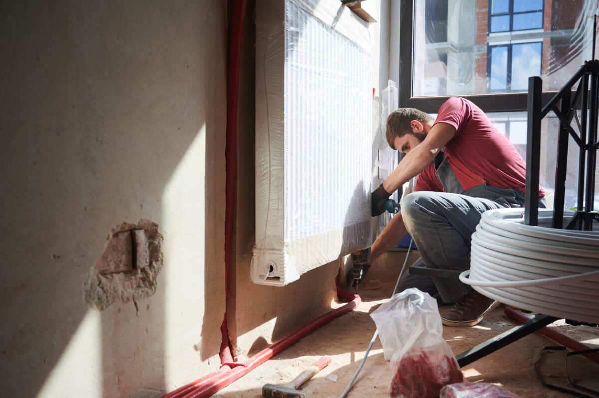 Ein Heizungsbauer installiert einen Heizköper an der Wand