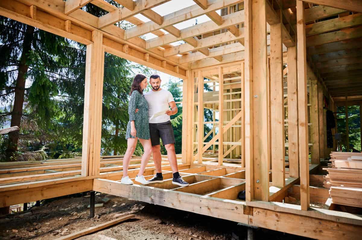 Eine Frau und ein Mann stehen im Grundgerüst eines Holzhaueses