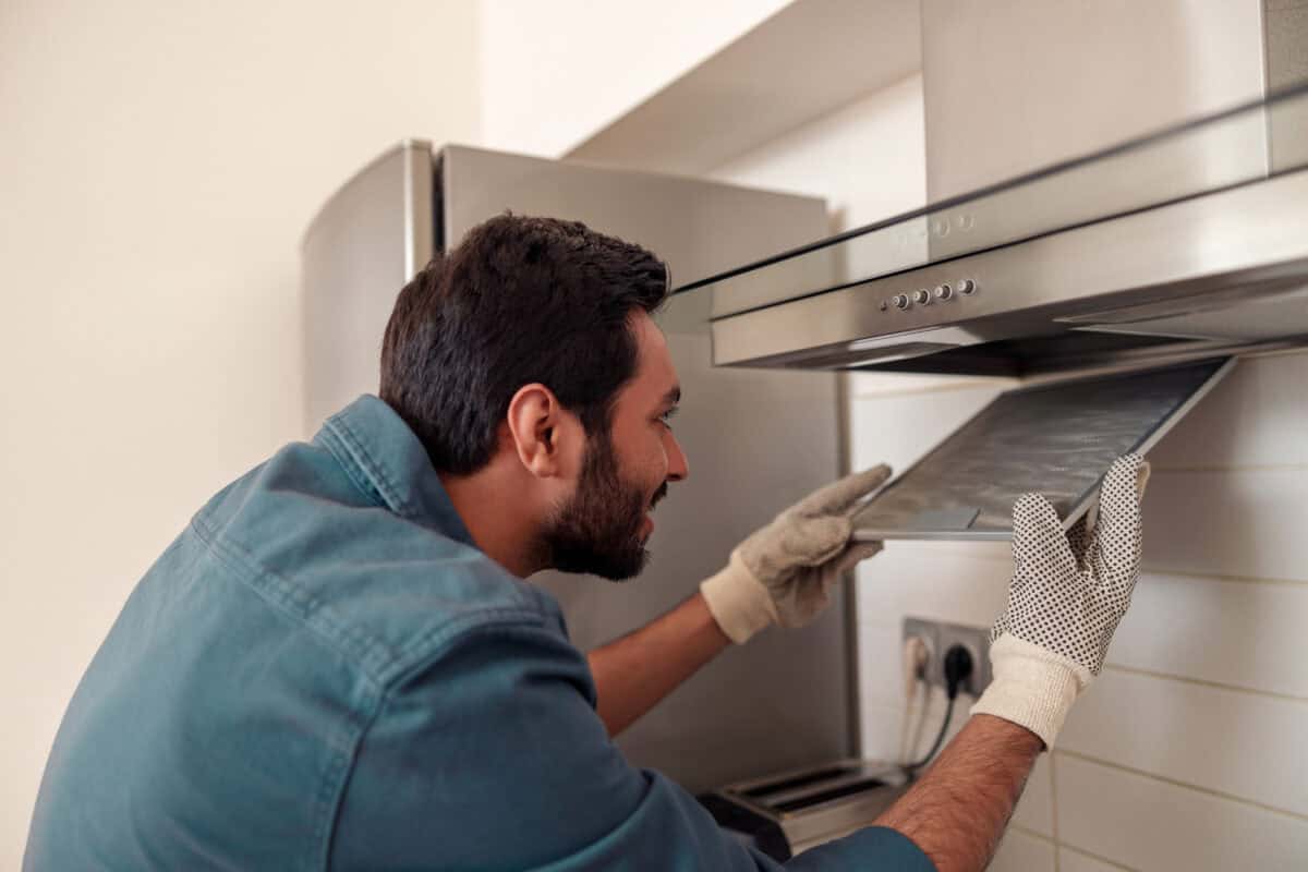 Ein Handwerker installiert eine Dunstabzugshaube